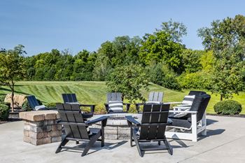 A patio with chairs and a table overlooking a field